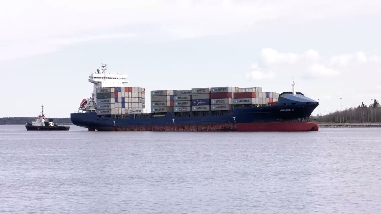 Containerfartyg till havs följt av en mindre båt.