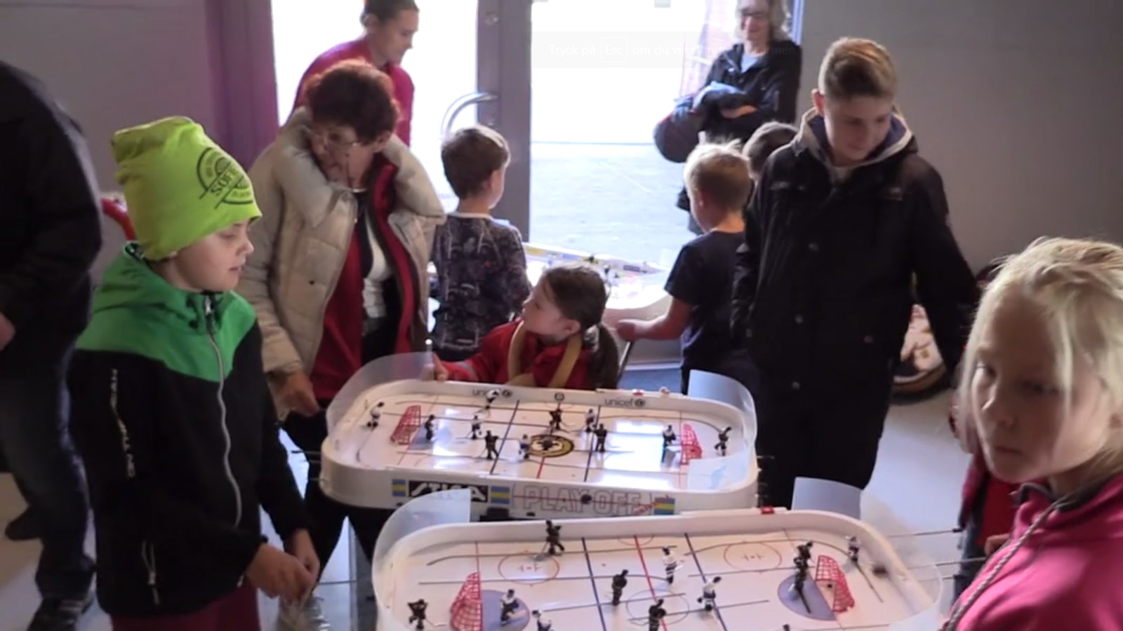 Barn och vuxna spelar bordshockeyspel.