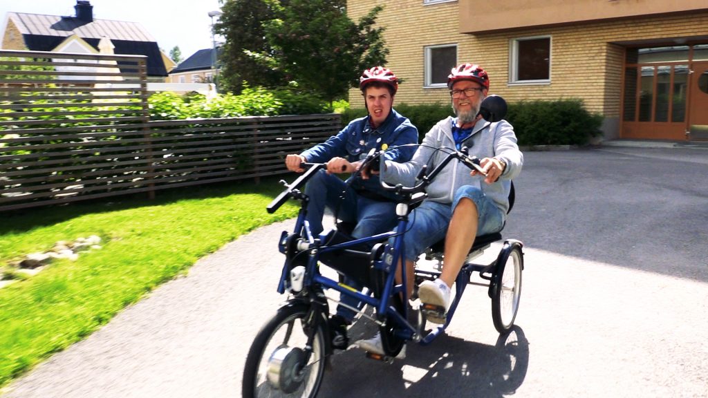 Två manliga personer cyklar tillsammans i en parcykel