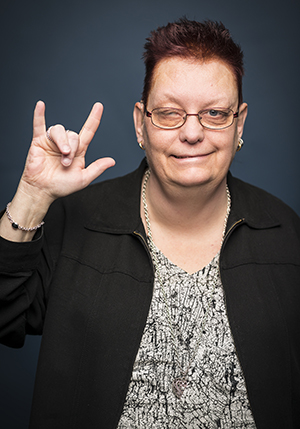 Porträttfoto i studio på Annica Torslund med ena ögat stängt och gör tecken med handen.