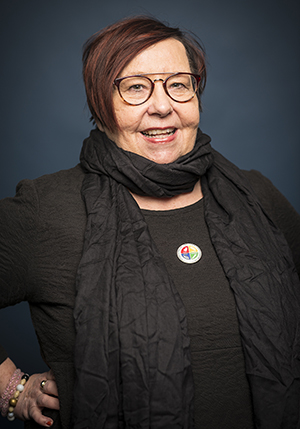 Porträttfoto i studio på Helena Näslund i svarta kläder, svart sjal runt halsen och handen på höften.