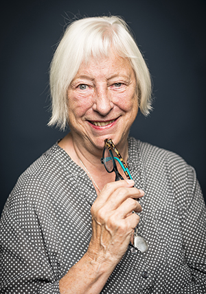 Porträttfoto i studio på Kerstin Monk som håller i ett par glasögon mot hakan.