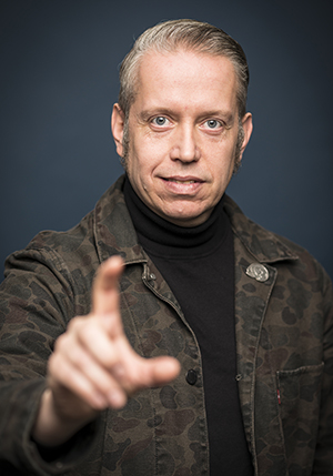 Porträttfoto i studio på Rolf Carl Verner som gör tecken med ena handen framför kameran.