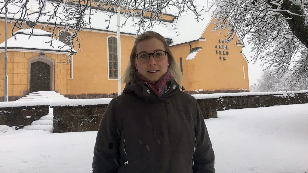 Närbild på en kvinna stående framför Staffankyrkan i Gävle, vintertid.