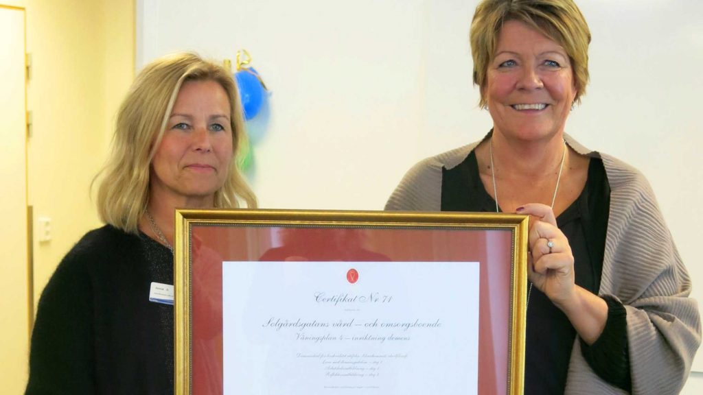Två kvinnor håller i en tavla med certifikat.
