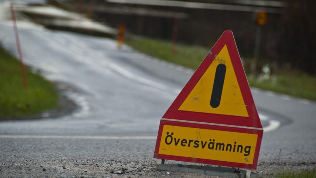 En vägskylt varnar för översvämning längre fram på vägen.