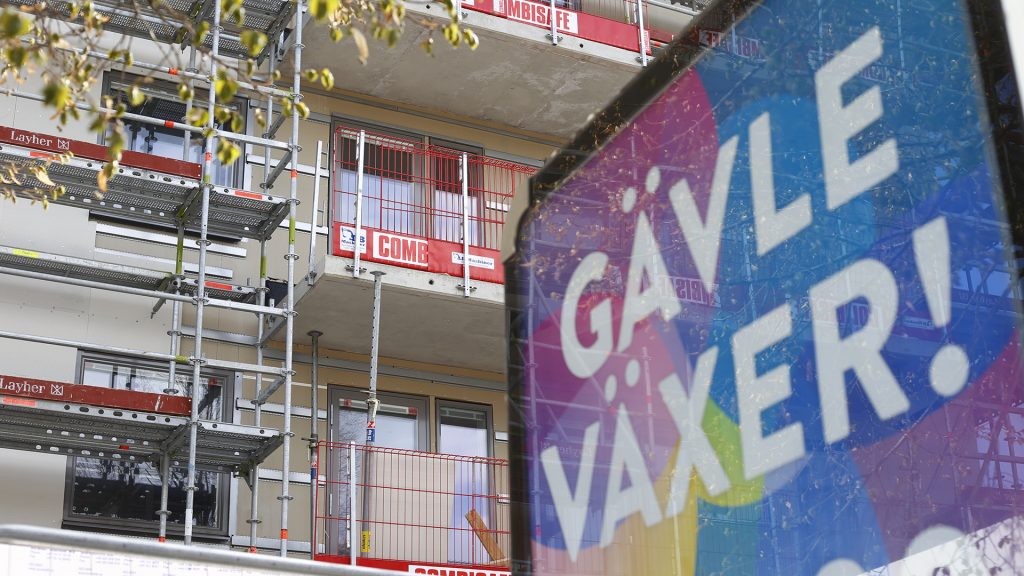 Gävle växer-skylt med ett lägenhetshus med byggställning i bakgrunden