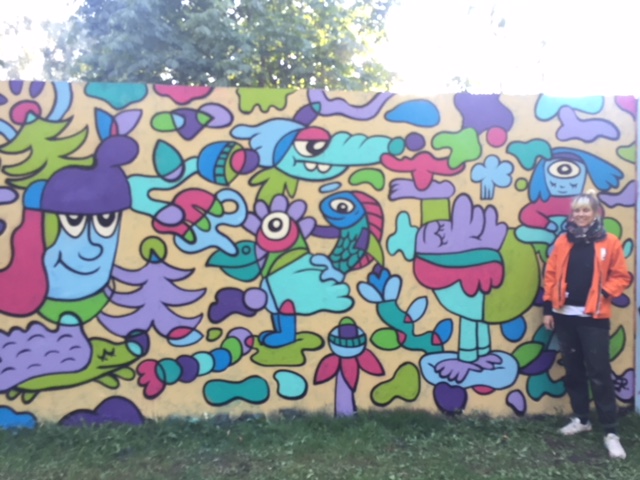 Kvinna stående framför en vägg med arrangerat klotter/graffiti