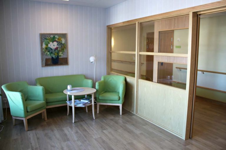 Sällskapsrum med gröna stoppade möbler.
