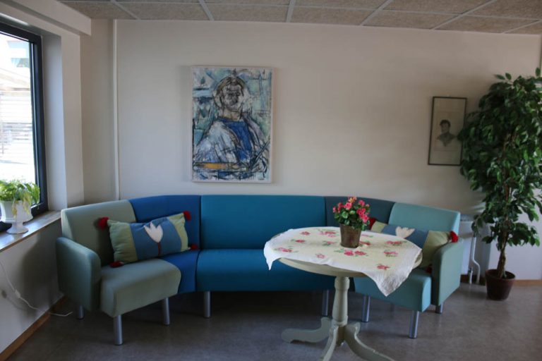 Sällskapsrum med blå soffa och konst på väggarna.