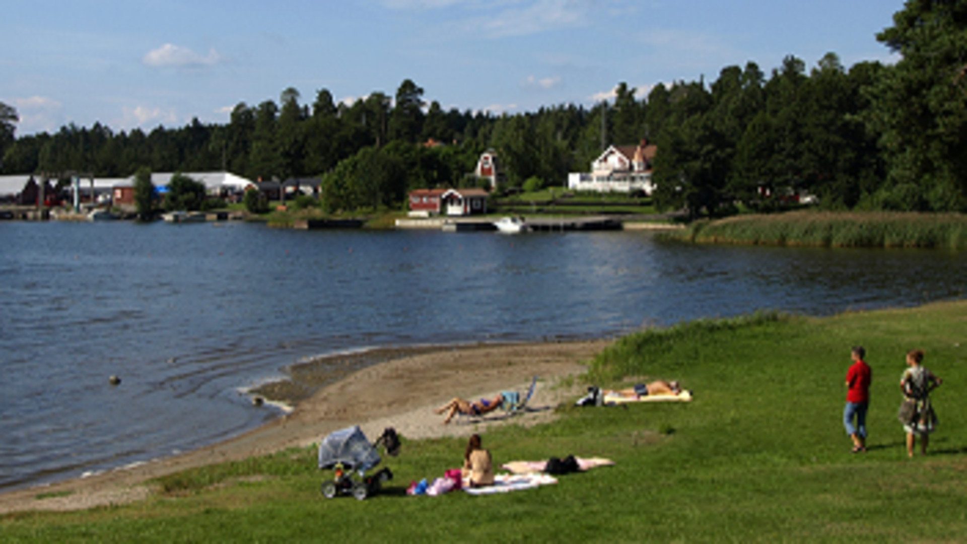 Vatten, sandstrand och gräsmatta vid Engesberg