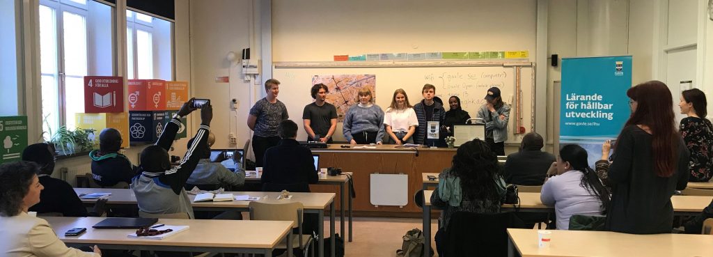 Sju personer stående längst fram i ett klassrum.