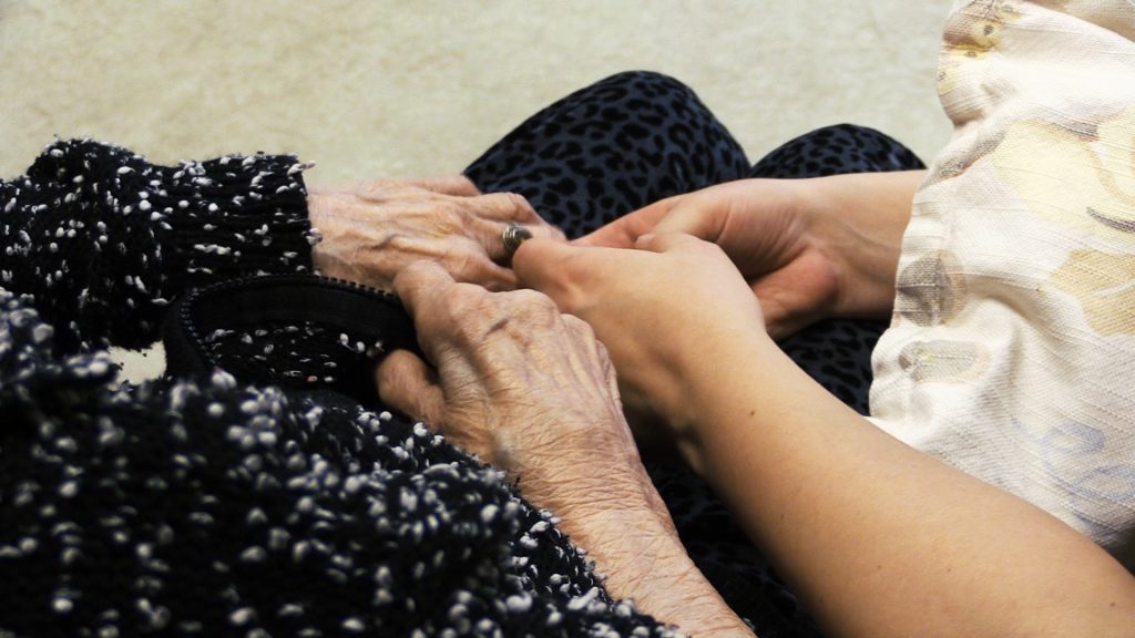 Händer från en yngre person håller i en äldres händer