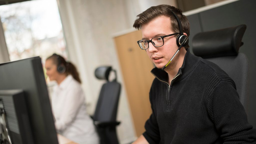 Man sitter framför dator och tar emot kundtjänstsamtal.