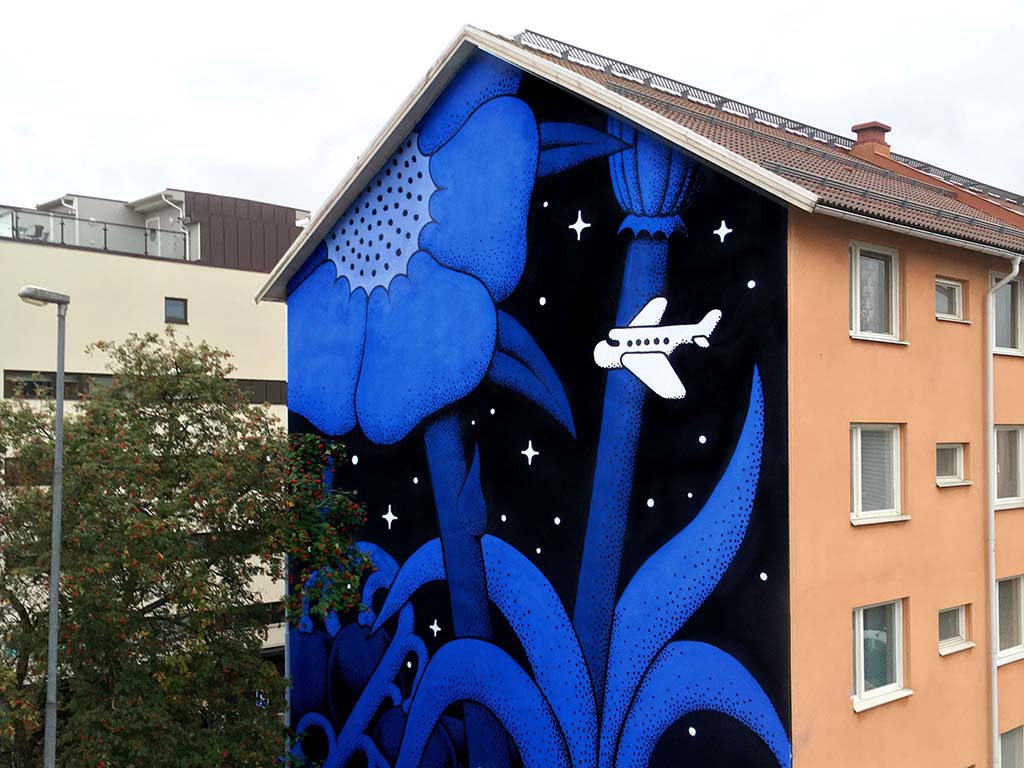 Muralmålning vid Brunnsgatan föreställer ett ensamt flygplan bland enorma växter mot en stjärnklar himmel.