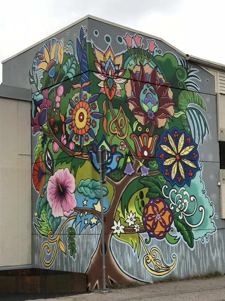 Muralmålning vid Staketgatan föreställer ett träd med olika utslagna blommor. 