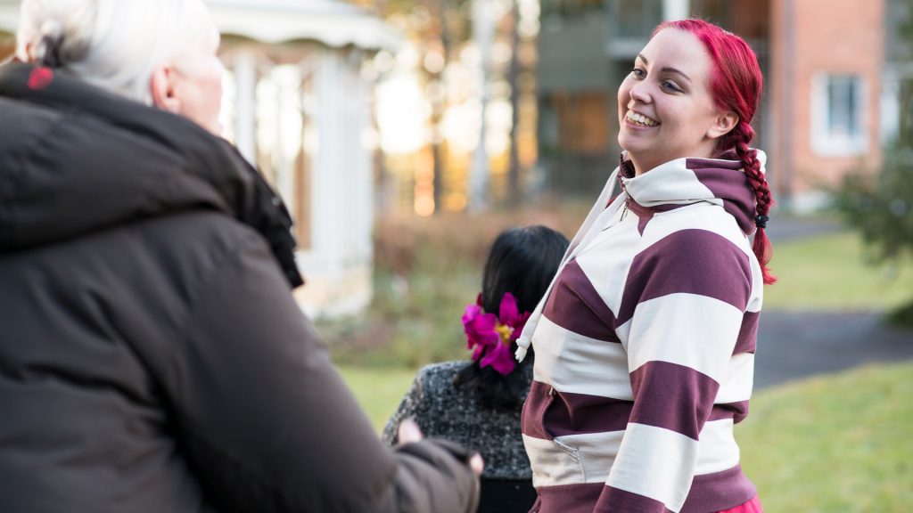 Ledsagare på promenad med kvinna i rullstol