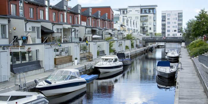 Kanal mellan hus på Gävle strand med bådar liggandes intill husen.