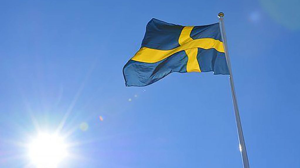 Svenska flaggan ur grodperspektiv mot blå himmel