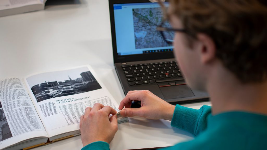 Elev sitter med elevdator samt kurslitteratur framför sig på bordet
