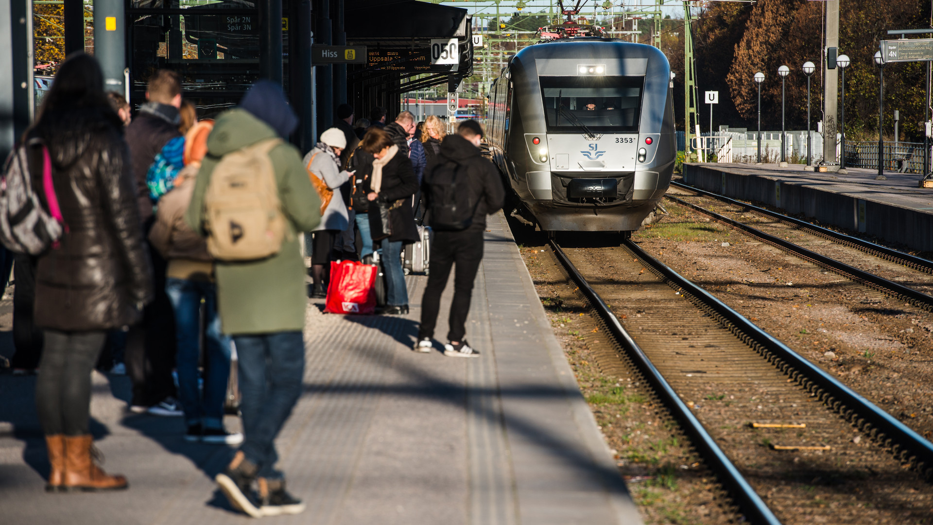 Tåg närmar sig perrong med väntande människor.