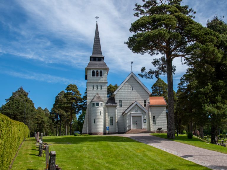 Bomhus kyrka med en grön gräsmatta och blå himmel