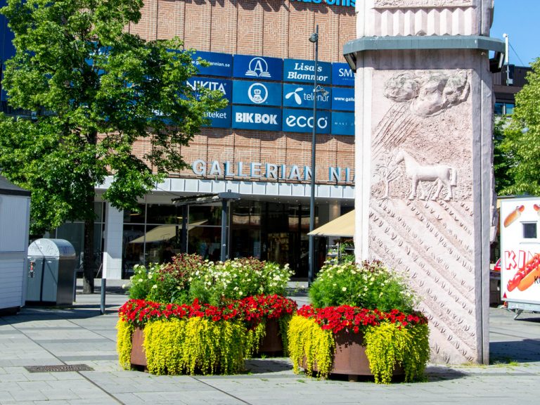 Blommor och staty utanför ingången till Gallerian Nian via mot Nygatan