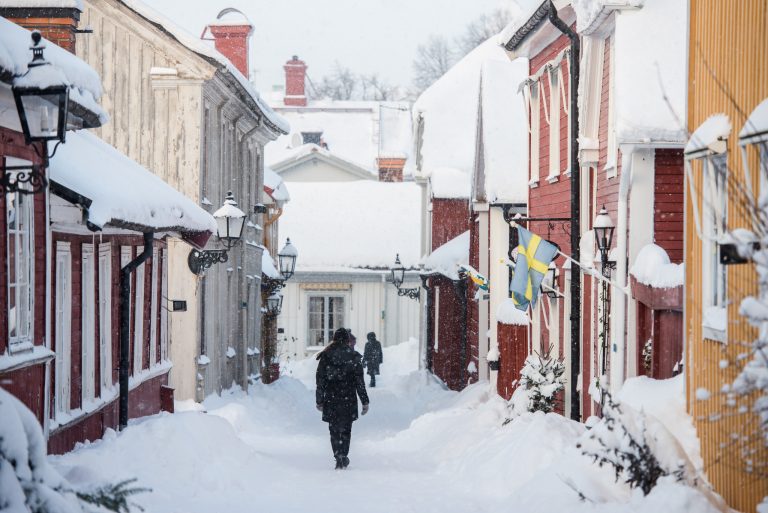 En snötäckt gata i Gamla Gefle. Två personer syns promenerande i gränden.