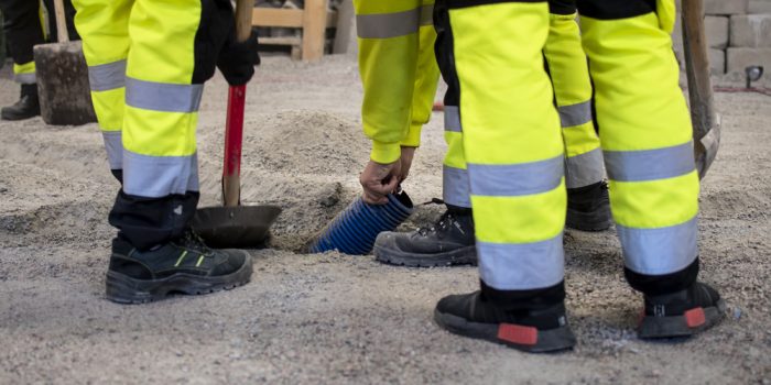 Byggarbetare lägger rör i marken.