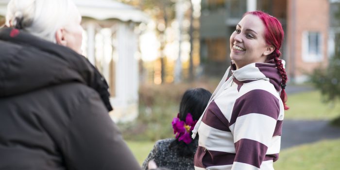 Ledsagare på promenad med kvinna i rullstol