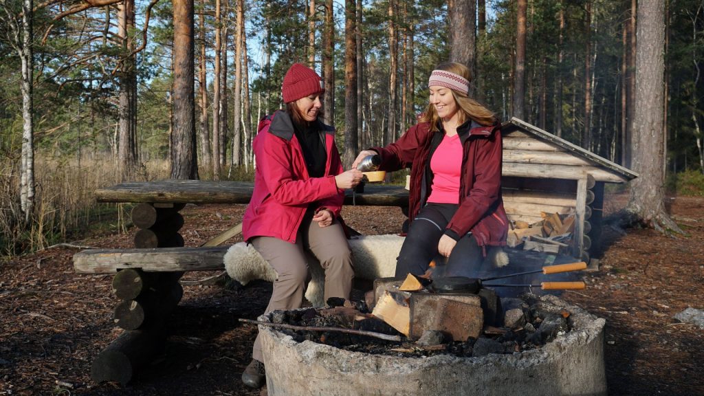 Två personer fikar i skogen