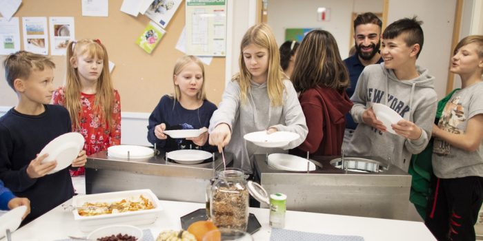 Skolelever som står och väntar i matkö.