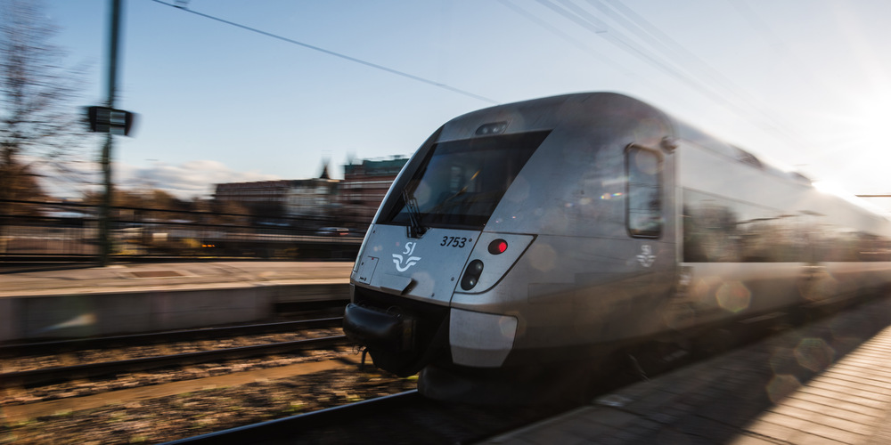 Tåg som åker in på Gävles tågstation. I bakgrunden syns en del av Dalapalatset på Brynäs.