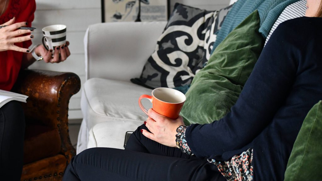 Två personer sitter och samtalar mitt emot varandra med en varsin kaffekopp.