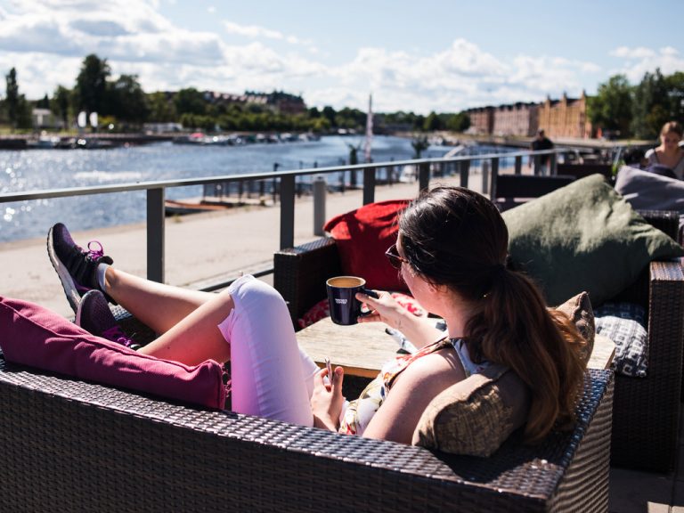 Kvinna som fikar på uteservering vid Gävle strand.