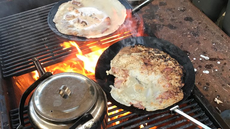 Matlagning över öppen eld i gjutjärnspannor.