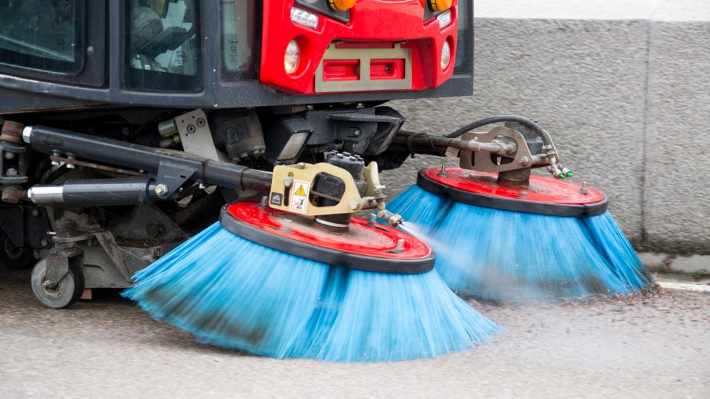 Fordon sopar upp sand på gata