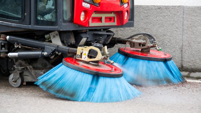 Fordon sopar upp sand på gata