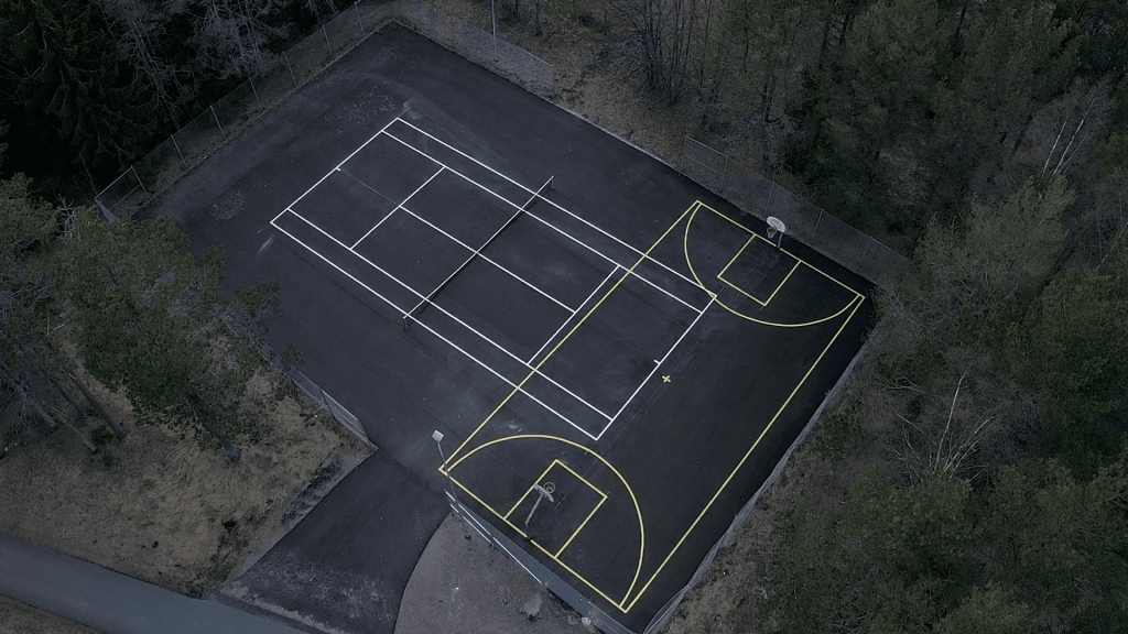 Drönarbild över en tennis- och basketplan i ett.