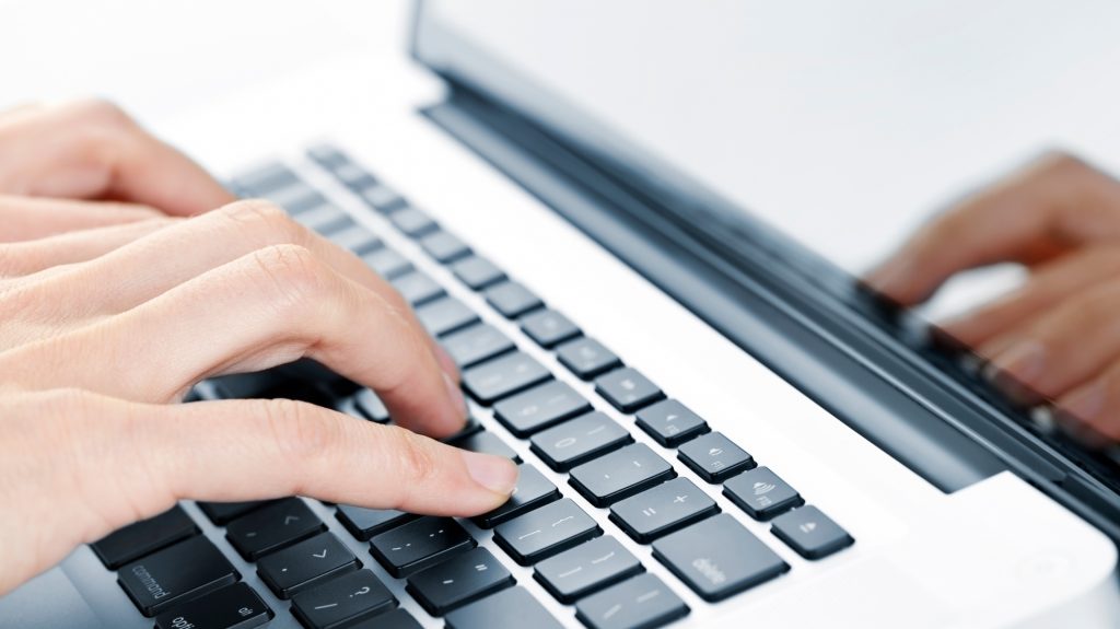 Skriver på bärbar dator närbild.