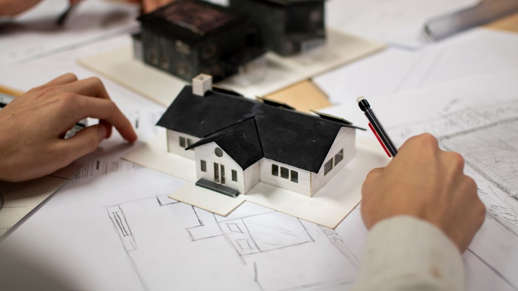 Närbild på arkitekturskisser och en husmodell i papp