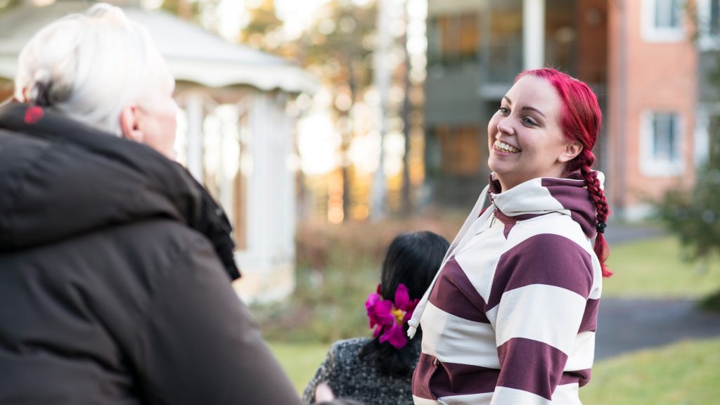 Ledsagare på promenad med kvinna i rullstol