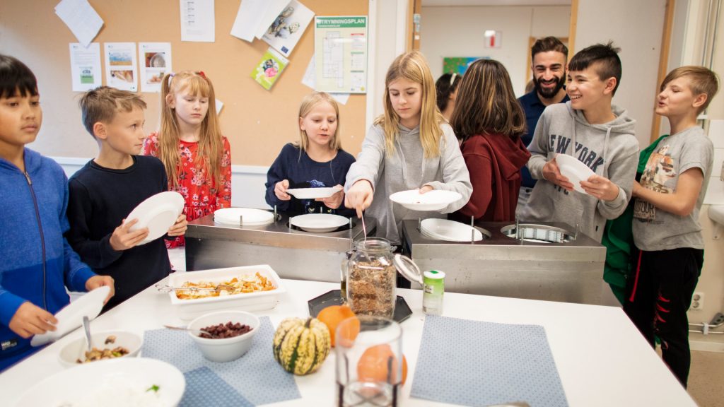 Skolelever som står och väntar i matkö.