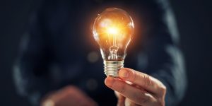 En hand som håller i en glödlampa som lyser.