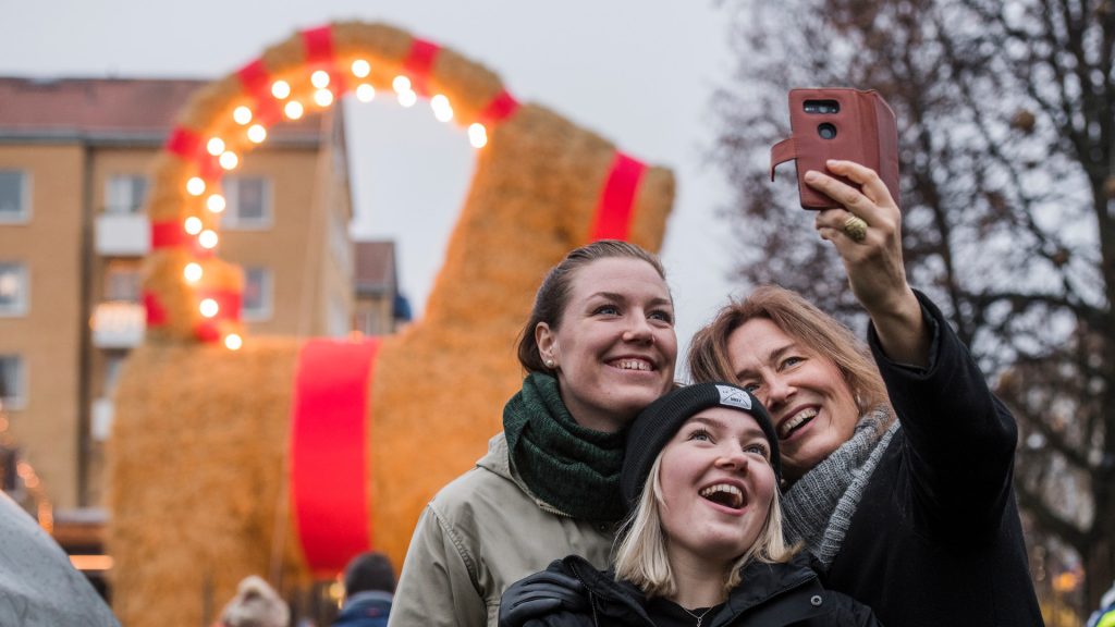 Tre personer tar en selfie framför Gävlebocken.