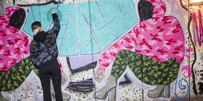 Tjej som sprayar graffitti på en vägg.