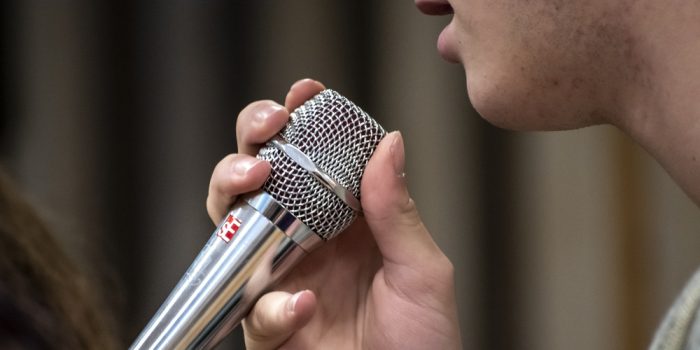 Närbild på hand som håller i en mikrofon.