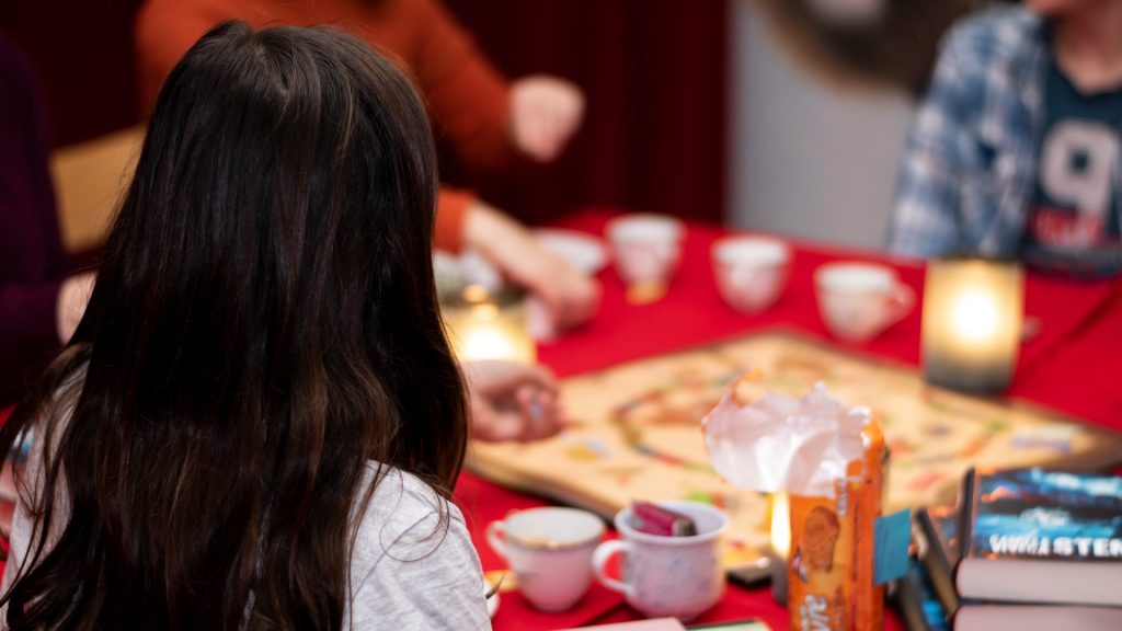 Personer sitter runt ett bord med sällskapsspel och böcker