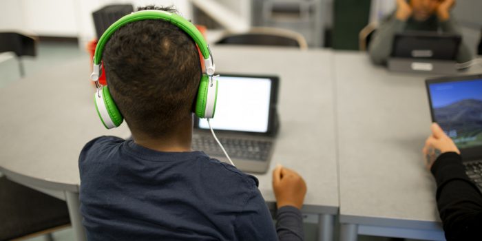 Bild på barn med hörlurar vid datorskärm.