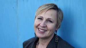 Porträtt på en kortklippt kvinna med blå bakgrund.